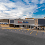 Exterior view of a retail shopping center building featuring a Prime Smile office sign and front parking spaces.